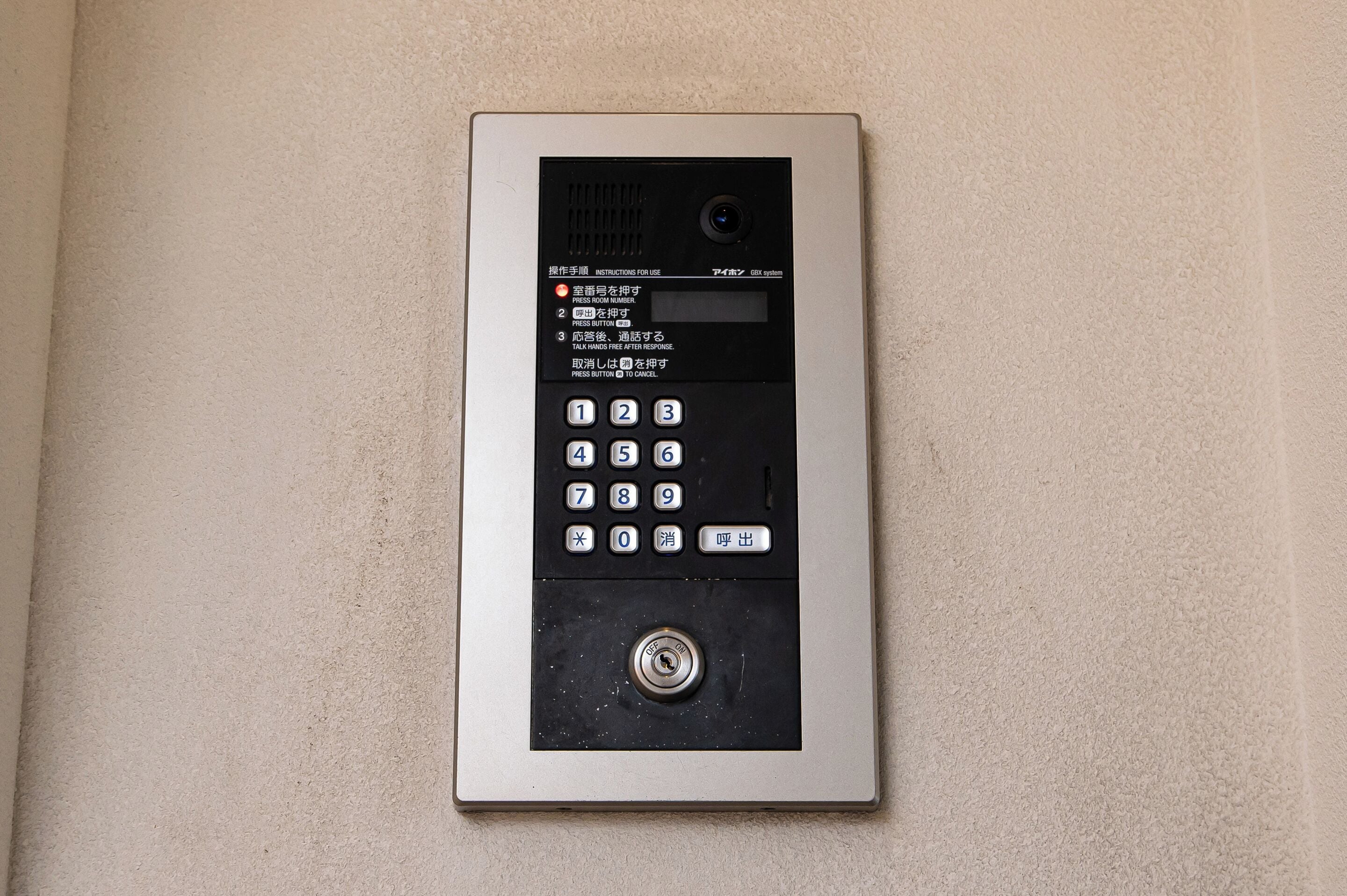 A wall-mounted intercom system with a keypad and a speaker.