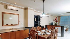 A modern kitchen with a dining area, a large mirror, and a chandelier. - PURI DARMO SERVICED RESIDENCE (Surabaya)