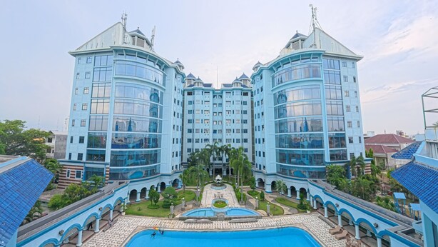 A large hotel with a central courtyard, a swimming pool, and a symmetrical facade. - PURI DARMO SERVICED RESIDENCE (Surabaya)