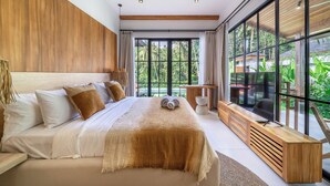 A modern bedroom with a large bed, wooden headboard, and a view of greenery through large windows. - Villa Verona (Ubud)