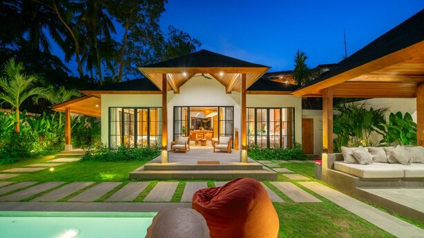 A modern house with a covered patio, a swimming pool, and lush greenery. - Villa Verona (Ubud)