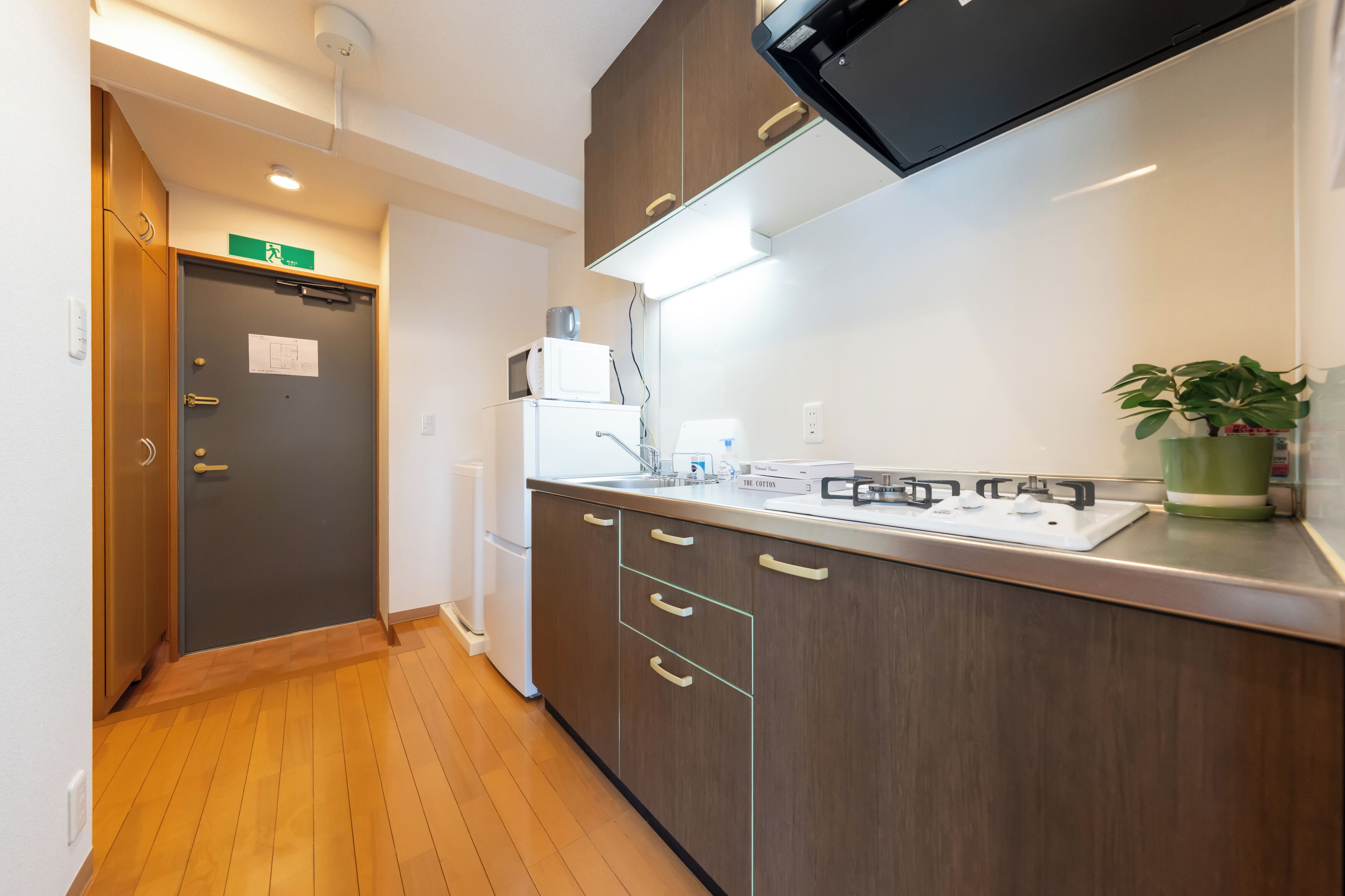 A modern kitchen with wooden cabinets, a built-in stove, and a small refrigerator.