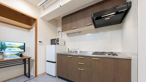 Une cuisine moderne avec des meubles en bois, un four à micro-ondes encastré, une cuisinière à gaz et un petit plan de travail.