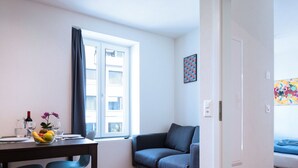 Uma sala de estar moderna com área de jantar, um sofá e uma janela com persianas.
