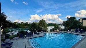 A swimming pool with lounge chairs and a view of a river. - Riverside Rhythm! Waterfront condo near Broadway, Nissan Stadium, Sounds, etc! (Nashville)