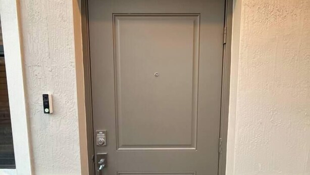 Puerta cerrada con teclado electrónico, un pequeño ventanal encima y una base de ladrillo.