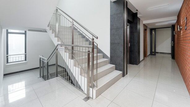 Een modern interieur met een trap, een groot raam en een bakstenen muur.