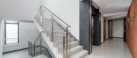 A modern interior with a staircase, a large window, and a brick wall.