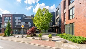 Een modern gebouw met een bordje voor 'May Apartments' en een zebrapad.