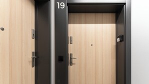 Et hotelværelse med en trædør, en sort dørkarm og nummer 19 på døren.