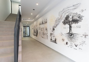 A hallway with a staircase, a wall with various illustrations and text, and a door labeled '15-26'. - Rondo Matecznego Studio #23 (Kraków)