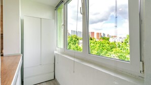 Una habitación con un ventanal grande, un armario blanco y suelo de madera.