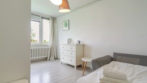 Un dormitorio con cama, cómoda, una mesita y una ventana con cortinas.