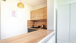 Una cocina con armarios de madera, un lavamanos, una estufa y una lámpara colgante.