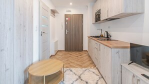 Une cuisine compacte avec un parquet en chevrons, une petite table ronde, un téléviseur et un four à micro-ondes.