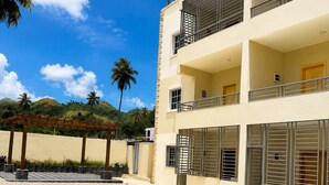 Ein mehrgeschossiges Gebäude mit Swimmingpool, Balkonen und Palmen im Hintergrund.