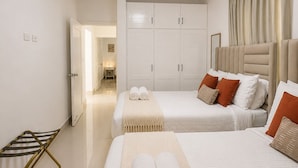 Ein Hotelzimmer mit zwei Betten, einem Kleiderschrank, einem Badezimmer und einer Sitzecke.