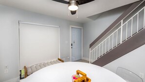 Ein Zimmer mit Deckenventilator, Treppe und Tür.