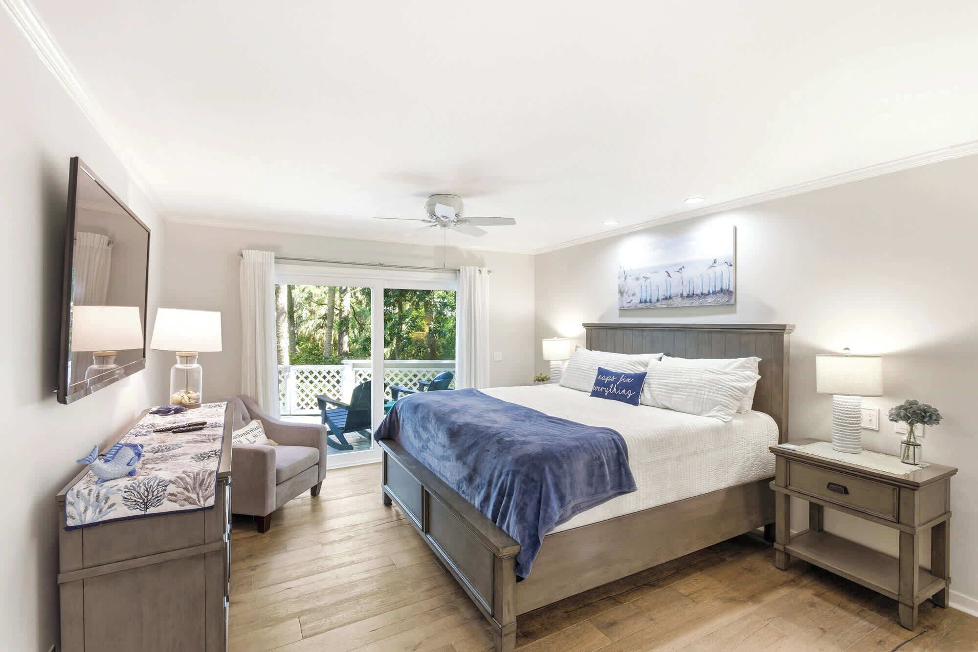 Une chambre à coucher comprenant un lit, un bureau, une chaise, une table de chevet et un ventilateur de plafond.