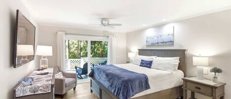 A bedroom with a bed, a desk, a chair, a nightstand, and a ceiling fan.