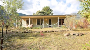 A house with a covered porch, a hammock, and a stone pathway leading to the entrance.