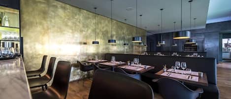Un interior de restaurante moderno con una zona de bar, mesas de comedor y sillas negras.