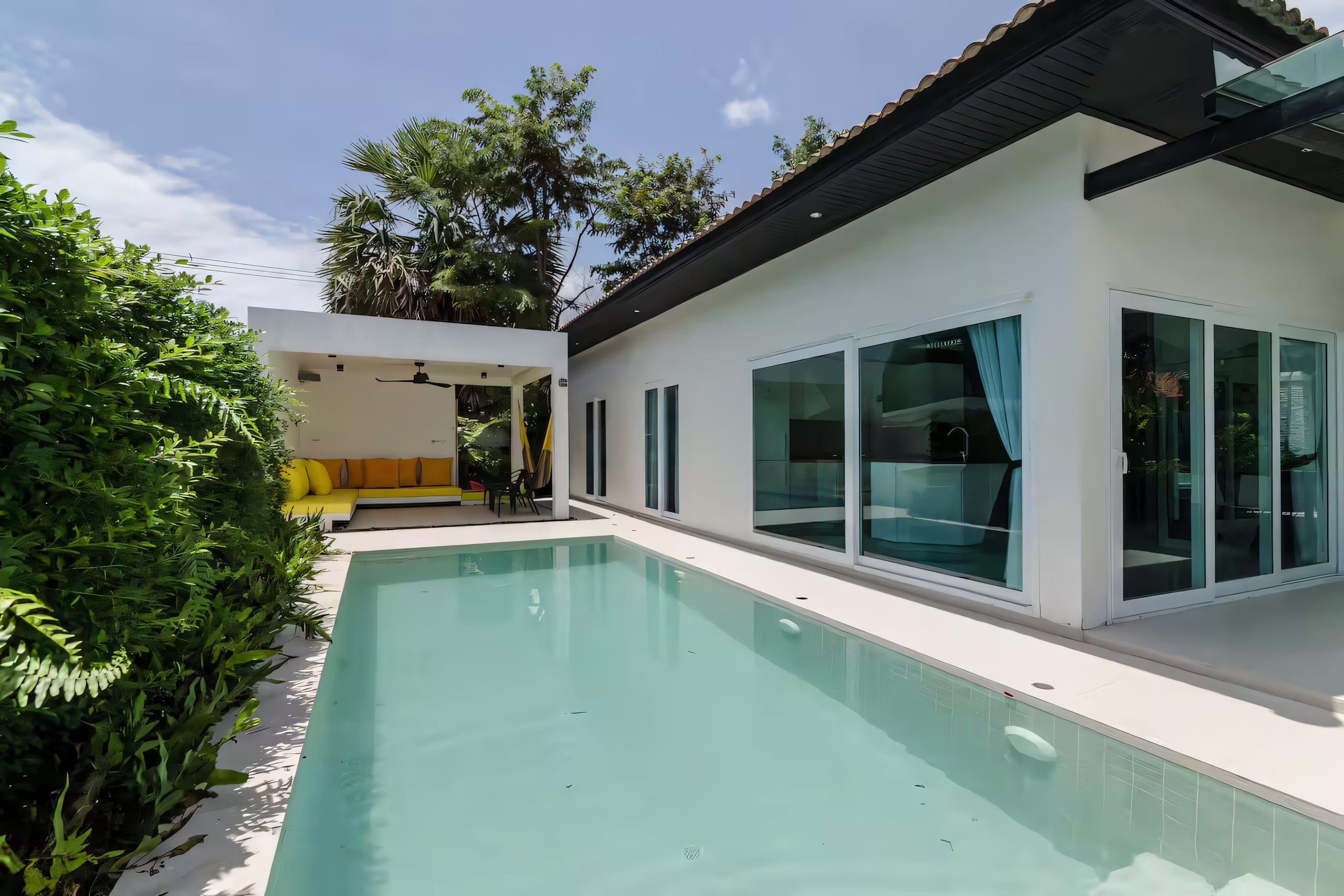 A modern house with a swimming pool, large windows, and a patio area.