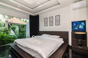 Habitación de hotel moderna con una cama grande, vistas al exterior con vegetación, una pared con citas motivacionales y un televisor en la pared.