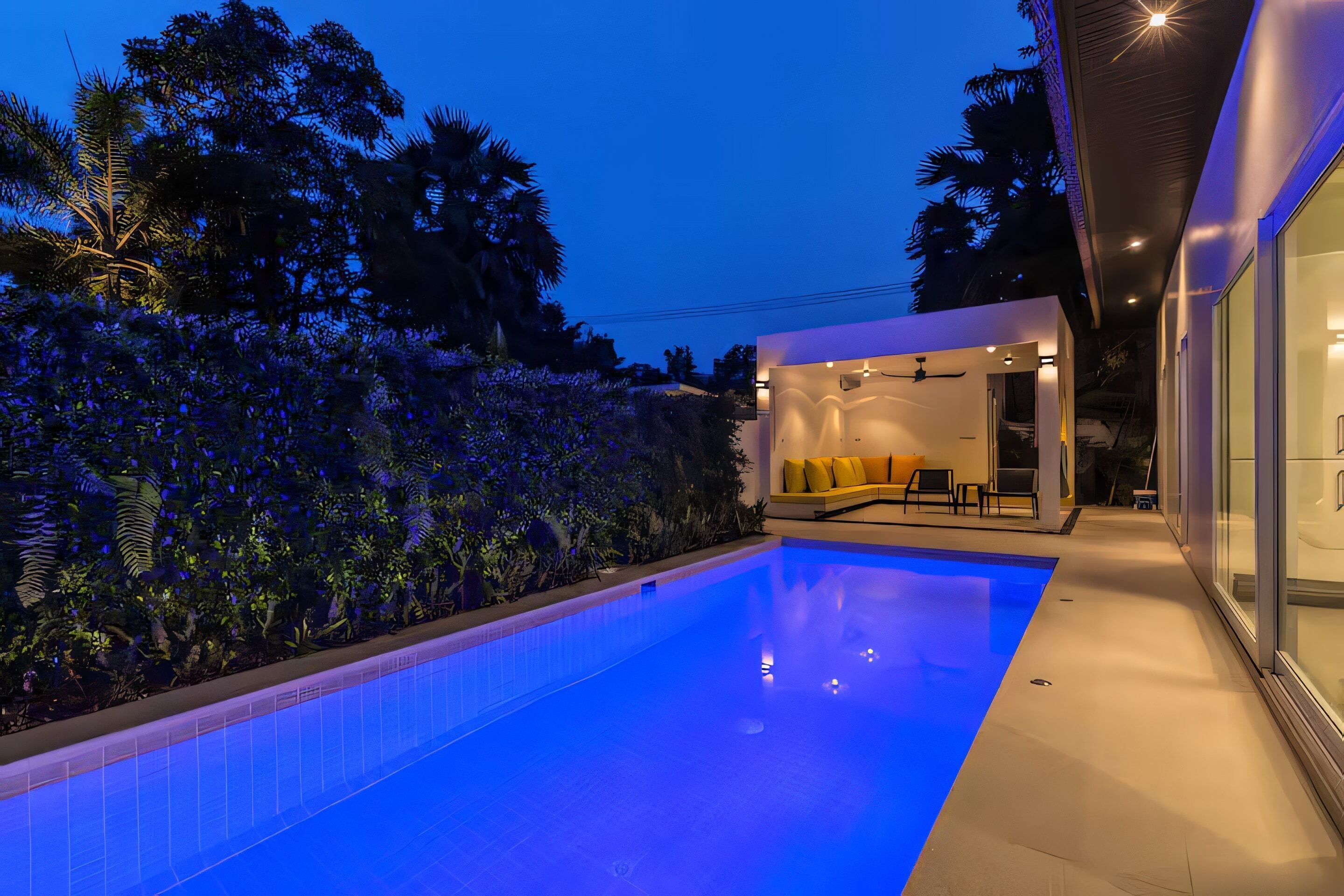 Ein moderner Poolbereich mit klarem Wasser, einer Glaswand und einem gut beleuchteten Innenraum.