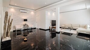 A modern living room with a white sofa, a glass coffee table, and a flat-screen TV. - Orchid Paradise Homes OPV03 (Hin Lek Fai)