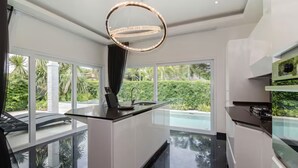 A modern kitchen with a central island, large windows, and a chandelier. - Orchid Paradise Homes OPV03 (Hin Lek Fai)