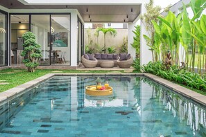 A swimming pool with a floating tray, outdoor seating, and lush greenery. - Villa Velora (Ubud)