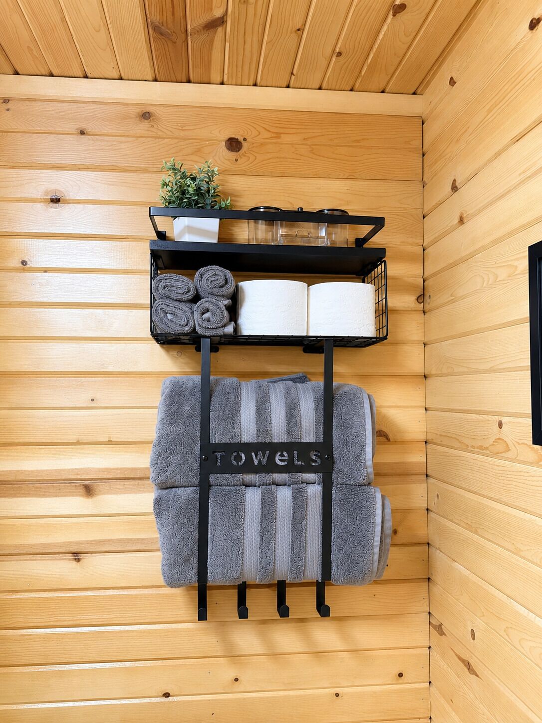 A wooden interior with a towel rack labeled 'TOWELS' holding multiple towels.