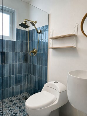 Ein Badezimmer mit Dusche, Toilette und einem weißen Waschbecken.