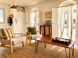 Ein Wohnzimmer mit einer Couch, Sesseln, einem Holztisch, einem Teppich und einem Schrank mit Dekoration.