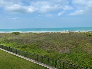 Eine Küstenlandschaft mit einer Rasenfläche, einem gepflasterten Weg und dem Meer im Hintergrund.