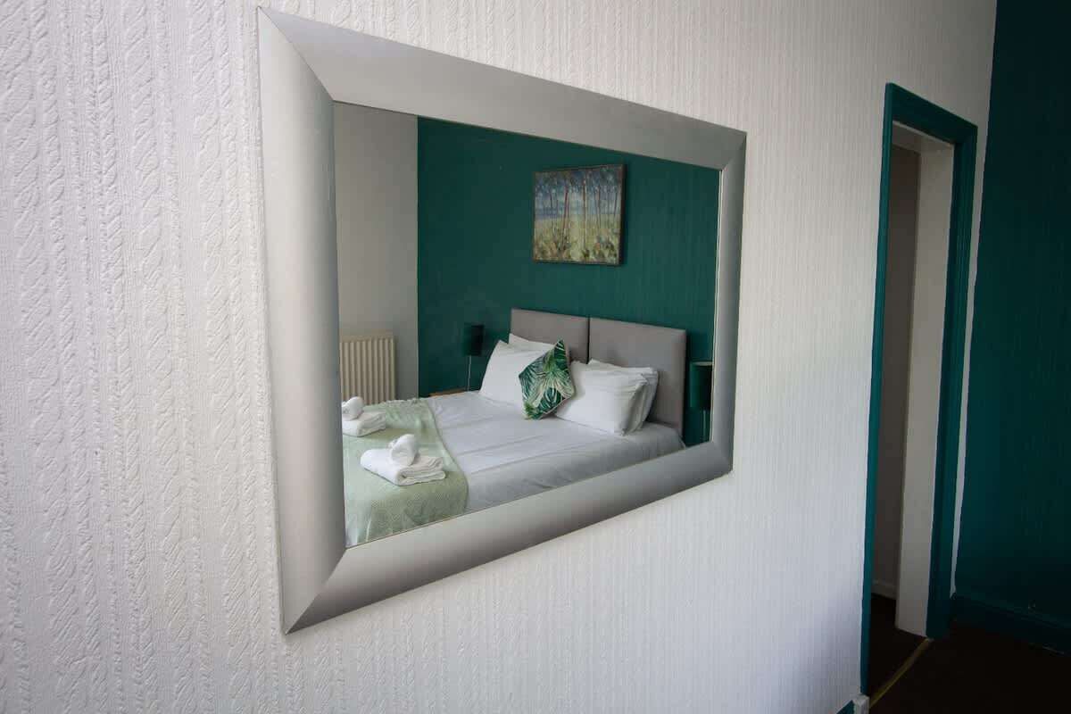 A bedroom with a bed, a green wall, and a painting.