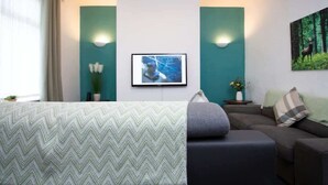 Een hotelkamer met een bed, een bank, een televisie aan de muur en een schilderij van een hert.