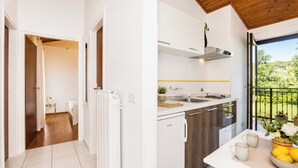 Cozinha moderna com forno embutido, pia e janela com vista para o verde.