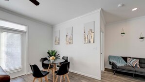 Una sala de estar moderna con comedor, sofá y obras de arte en las paredes.