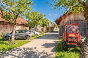 Een landelijke straat met een geparkeerde auto en een rode tractor.