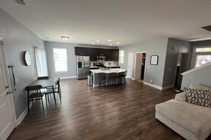 Uma sala de estar ampla com cozinha, mesa de jantar e sofá.