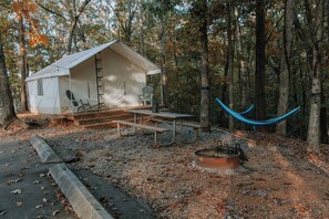 A rustic cabin with a porch, a hammock, and a fire pit.