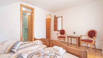 Una camera d'albergo con un letto, due sedie, un tavolino e uno specchio.
