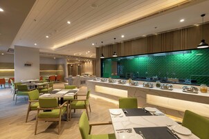 Un restaurante moderno con sillas verdes, una barra de mármol y un revestimiento de pared verde tipo espiga.