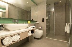 Un baño moderno con un lavamanos grande, inodoro y cabina de ducha.