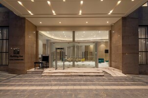 Entrada de un hotel con puerta de cristal, un mostrador de recepción y una zona de estar en el interior.