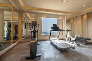 A modern gym with exercise equipment, large windows, and a view of the city. - Holiday Inn Katra Vaishno Devi (Reasi)