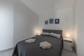 Ein modernes Schlafzimmer mit einem großen Bett, zwei Nachttischen und drei gerahmten Bildern an der Wand.