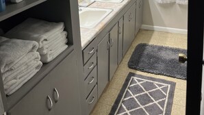 A bathroom with a sink, mirror, and towel storage.